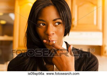 Stock Image - Young woman licking finger. Fotosearch