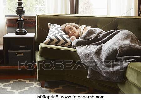 Young woman lying on living room sofa wrapped in blanket View Large Photo Image Stock Photography - Young woman lying on living room sofa wrapped in blanket. Fotosearch
