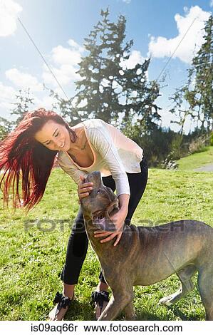 Young woman petting her dog in park View Large Photo Image Stock Photography - Young woman petting her dog in park. Fotosearch