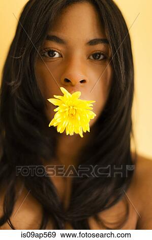 Stock Photo - Young woman posing with flower in her mouth. Fotosearch