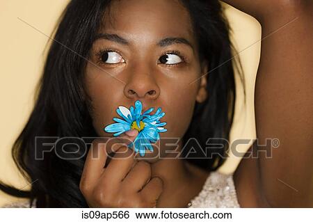 Stock Photograph - Young woman posing with flower in mouth. Fotosearch