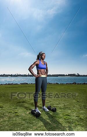 Young woman with hands on hips preparing to train with dumb bells at coast View Large Photo Image Stock Photo - Young woman with hands on hips preparing to train with dumb bells at coast. Fotosearch