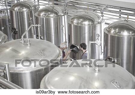 Stock Photo - Brewer cleaning out a stainless steel tank in the brewery. Fotosearch