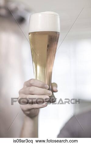 Brewer in brewery holding up a glass of beer View Large Photo Image Stock Photography - Brewer in brewery holding up a glass of beer. Fotosearch