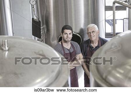 Brewers in brewery next to stainless steel tanks View Large Photo Image Stock Photo - Brewers in brewery next to stainless steel tanks. Fotosearch