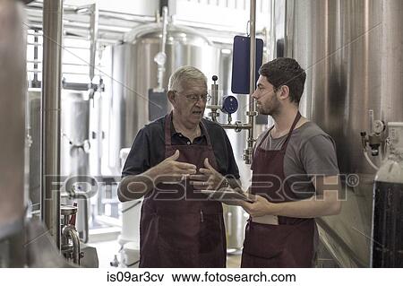 Brewers in brewery standing next to stainless steel tanks View Large Photo Image Stock Photo - Brewers in brewery standing next to stainless steel tanks. Fotosearch