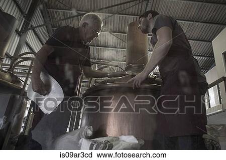 Stock Image - Brewers looking into brewing machine. Fotosearch