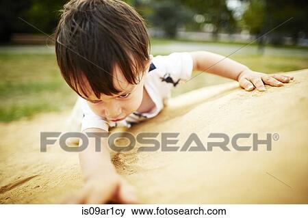 Stock Photo - Close up of boy climbing a sand rock. Fotosearch