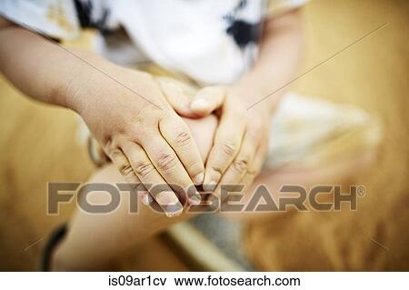 Stock Photo - Close up of boy holding his knee with his hands. Fotosearch