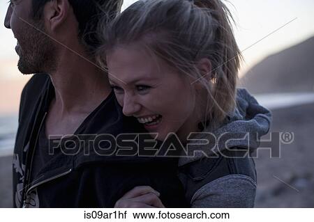 Stock Image - "Couple hugging on beach, Malibu, California, USA". Fotosearch