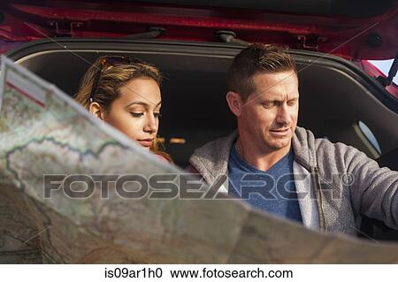 Stock Image - Couple reading map behind vehicle. Fotosearch