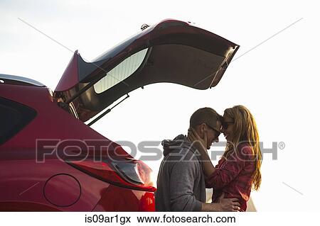 Stock Photo - Couple relaxing behind vehicle. Fotosearch