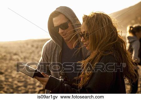 Stock Photo - Couple using digital tablet on beach. Fotosearch