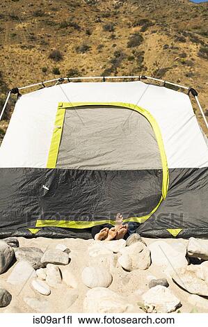 Stock Image - "Couple's feet sticking out of tent, Malibu, California, USA". Fotosearch