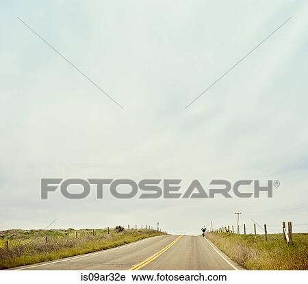 Stock Image - "Distant view of cyclist on highway 1, Big Sur, California, USA". Fotosearch