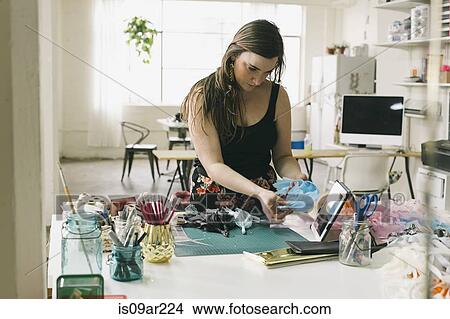 Picture - Female designer following instructions on digital tablet in design studio. Fotosearch