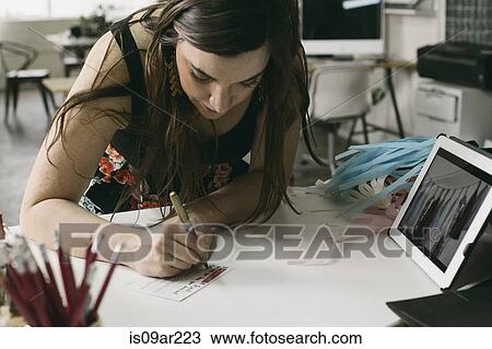 Stock Image - Female designer making note in design studio. Fotosearch