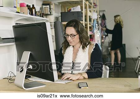 Stock Photo - Female office worker at desk in design studio. Fotosearch