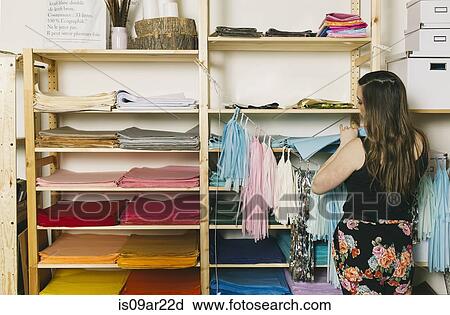 Stock Image - Female textile designer selecting textiles in design studio. Fotosearch