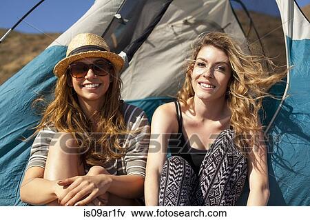 Stock Photo - Girlfriends relaxing beside tent. Fotosearch