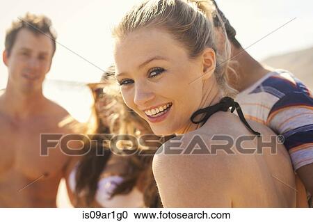 Stock Image - Group of friends on vacation at beach. Fotosearch