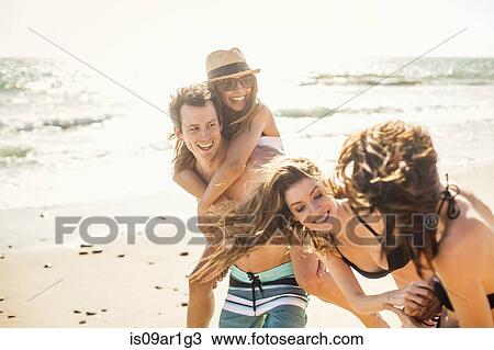 Stock Image - Group of friends on vacation at beach. Fotosearch
