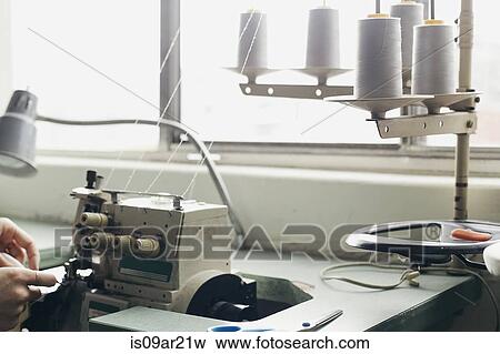 Stock Photo - Hands of young female seamstress sewing textile on sewing machine. Fotosearch