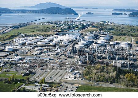 Stock Image - High angle view of coastal oil refinery with white oil storage tanks. Fotosearch
