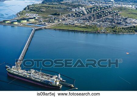 Stock Image - High angle view of oil transfer between oil refinery and oil tanker. Fotosearch