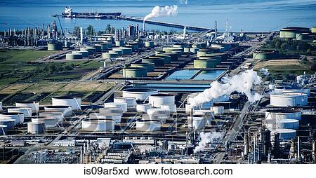 Stock Image - High angle view of white oil storage tanks in coastal oil refinery. Fotosearch