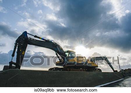 Low angle silhouetted view of two excavators parked back to back View Large Photo Image Stock Image - Low angle silhouetted view of two excavators parked back to back. Fotosearch