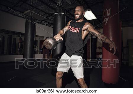 Male boxer lifting kettlebell with gritted teeth in gym View Large Photo Image Stock Image - Male boxer lifting kettlebell with gritted teeth in gym. Fotosearch