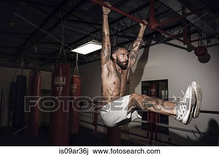 Stock Image - Male boxer training on bar in gym. Fotosearch