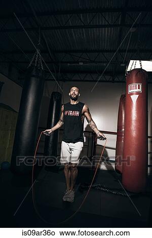 Picture - Male boxer training on skipping rope in gym. Fotosearch