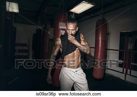 Male boxer wiping sweat from face in gym View Large Photo Image Stock Photography - Male boxer wiping sweat from face in gym. Fotosearch
