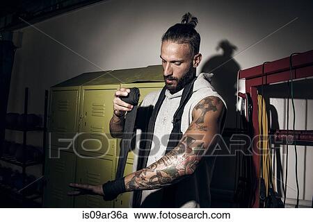 Stock Image - Male boxer with bandaging hands in gym. Fotosearch