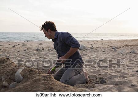 Man digging into sand on beach View Large Photo Image Stock Image - Man digging into sand on beach. Fotosearch