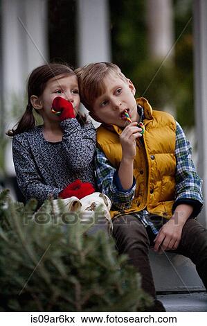 Stock Photo - Portrait of a boy and girl eating festive candy canes. Fotosearch