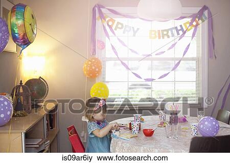 Stock Photo - Portrait of blonde girl sitting at birthday party table. Fotosearch