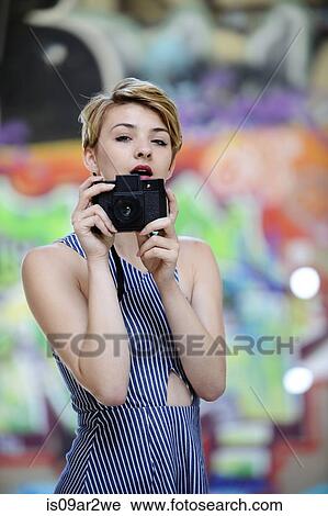Portrait of cool teenage girl holding up camera in front of graffiti wall View Large Photo Image Stock Image - Portrait of cool teenage girl holding up camera in front of graffiti wall. Fotosearch