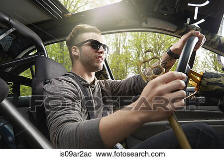 Stock Image - Portrait of man driving wearing sunglasses. Fotosearch