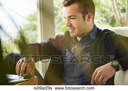 Stock Photo - Portrait of man sitting on floor using laptop. Fotosearch