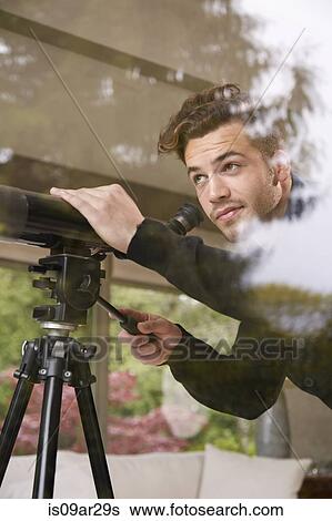 Portrait of man using telescope looking out of window View Large Photo Image Stock Photograph - Portrait of man using telescope looking out of window. Fotosearch