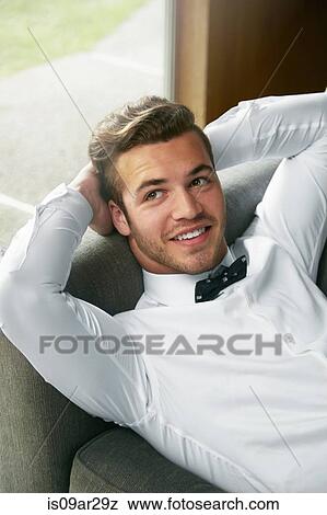 Portrait of man wearing bow tie reclining on sofa with hands behind head View Large Photo Image Stock Photo - Portrait of man wearing bow tie reclining on sofa with hands behind head. Fotosearch
