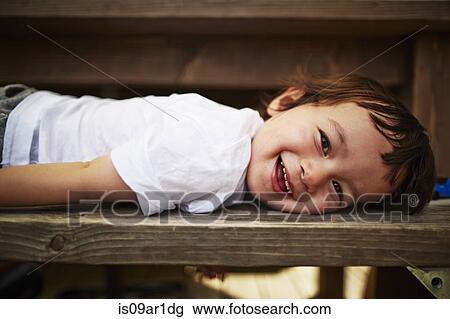 Portrait of smiling boy laying on bench View Large Photo Image Stock Image - Portrait of smiling boy laying on bench. Fotosearch