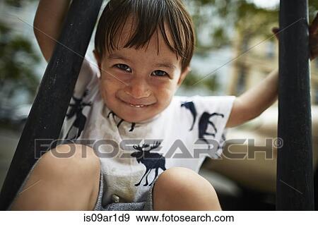 Portrait of smiling boy sat between railings View Large Photo Image Stock Photo - Portrait of smiling boy sat between railings. Fotosearch
