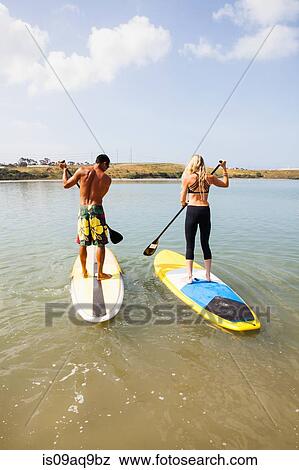 "Rear view of couple standup paddleboarding, Carlsbad, California, USA" View Large Photo Image Stock Photo - "Rear view of couple standup paddleboarding, Carlsbad, California, USA". Fotosearch