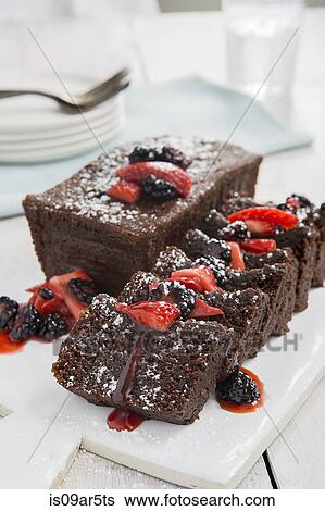 Stock Photograph - Sliced chocolate cake with strawberries and blackberries. Fotosearch