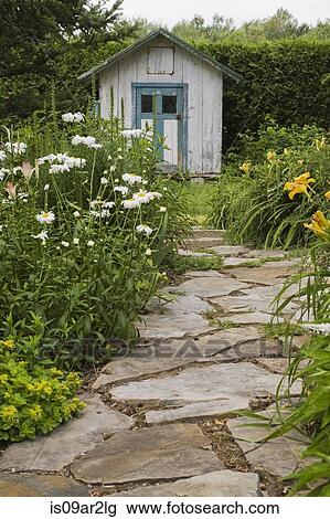 Stock Image - Stone paving leading to garden shed. Fotosearch