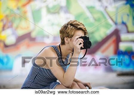 Stylish teenage girl photographing with camera in front of graffiti wall View Large Photo Image Stock Image - Stylish teenage girl photographing with camera in front of graffiti wall. Fotosearch